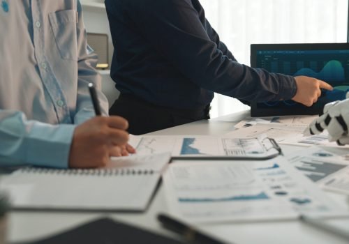 Team of business professionals collaborating in a modern office with futuristic technology analyzing data on screens and discussing strategies for growth. Noogenesis